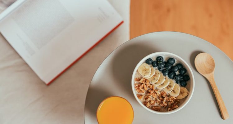 Top view of healthy breakfast with oatmeal, fresh fruit, and orange juice on a tray.